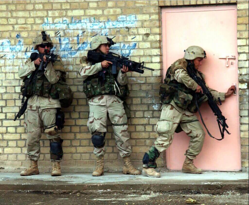 three soldiers ready to breach a building and clear the structure through a red door Bellavia